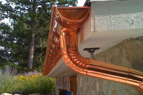 Copper downspout curving off a gutter